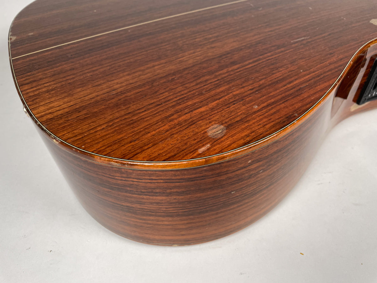 Close-up of the guitar's lower bout, showing the dark wood grain, binding, and several dings and scratches on the body.
