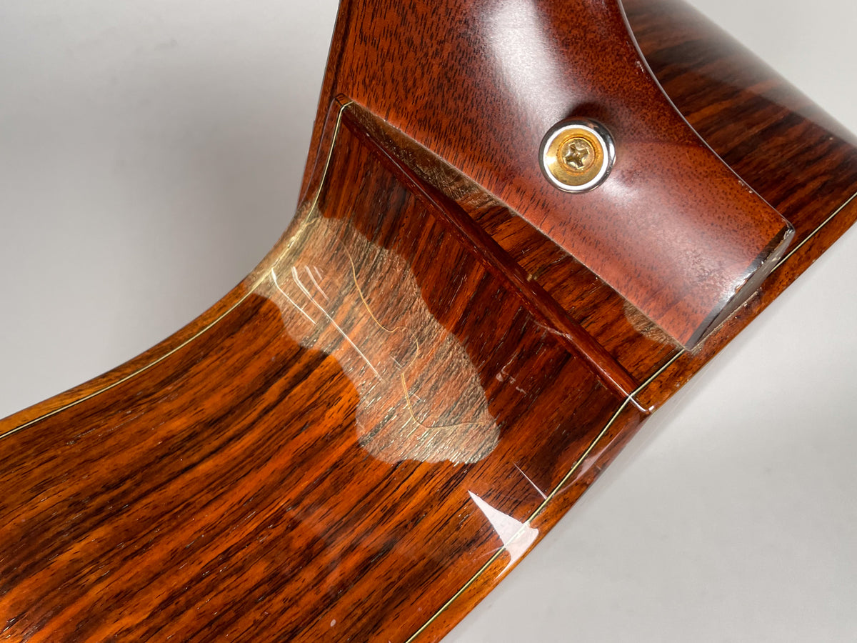 Close-up of the guitar's lower bout and neck heel, showing finish wear and checking on the dark wood grain.