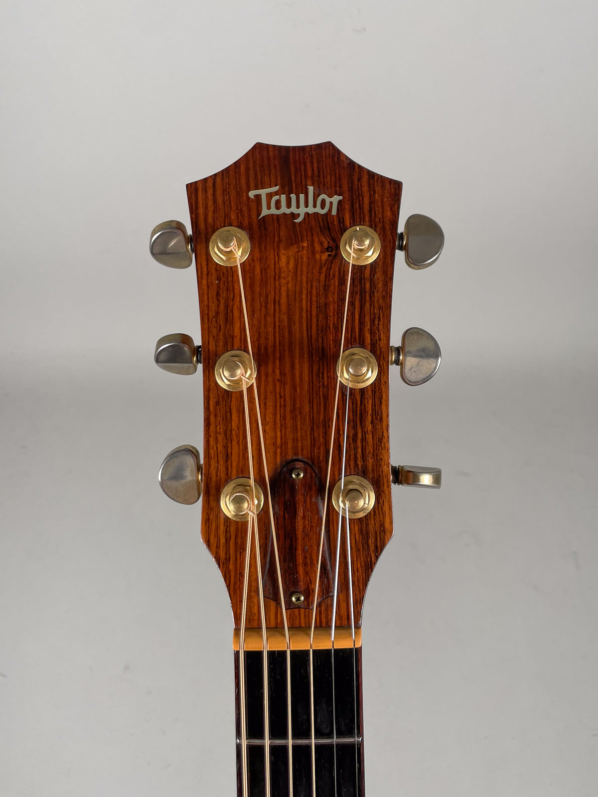 Close-up of the guitar's dark wood headstock with gold tuners and light strings, showing light wear on the tuner buttons.