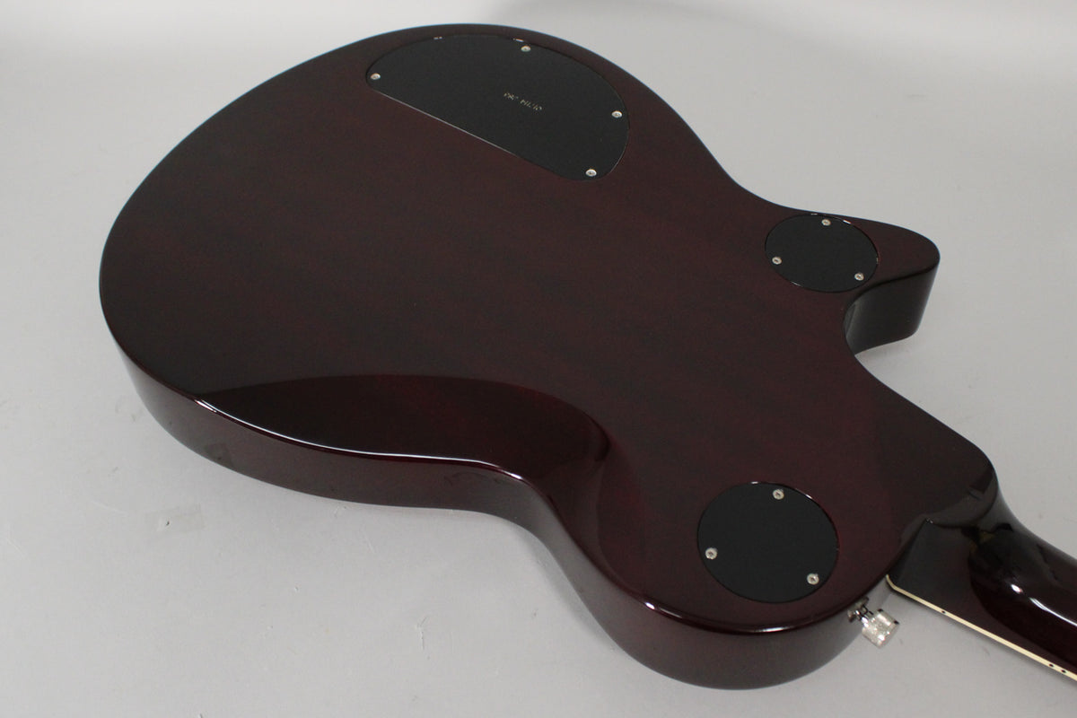 The back of the transparent red guitar body, angled from the lower right, shows three black control cavity covers and a strap button.