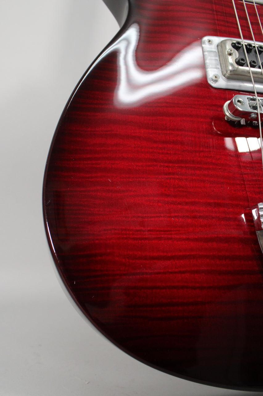 Close-up of the transparent red finish on the guitar's body, showing wood grain, light surface scratches, and a chrome pickup.