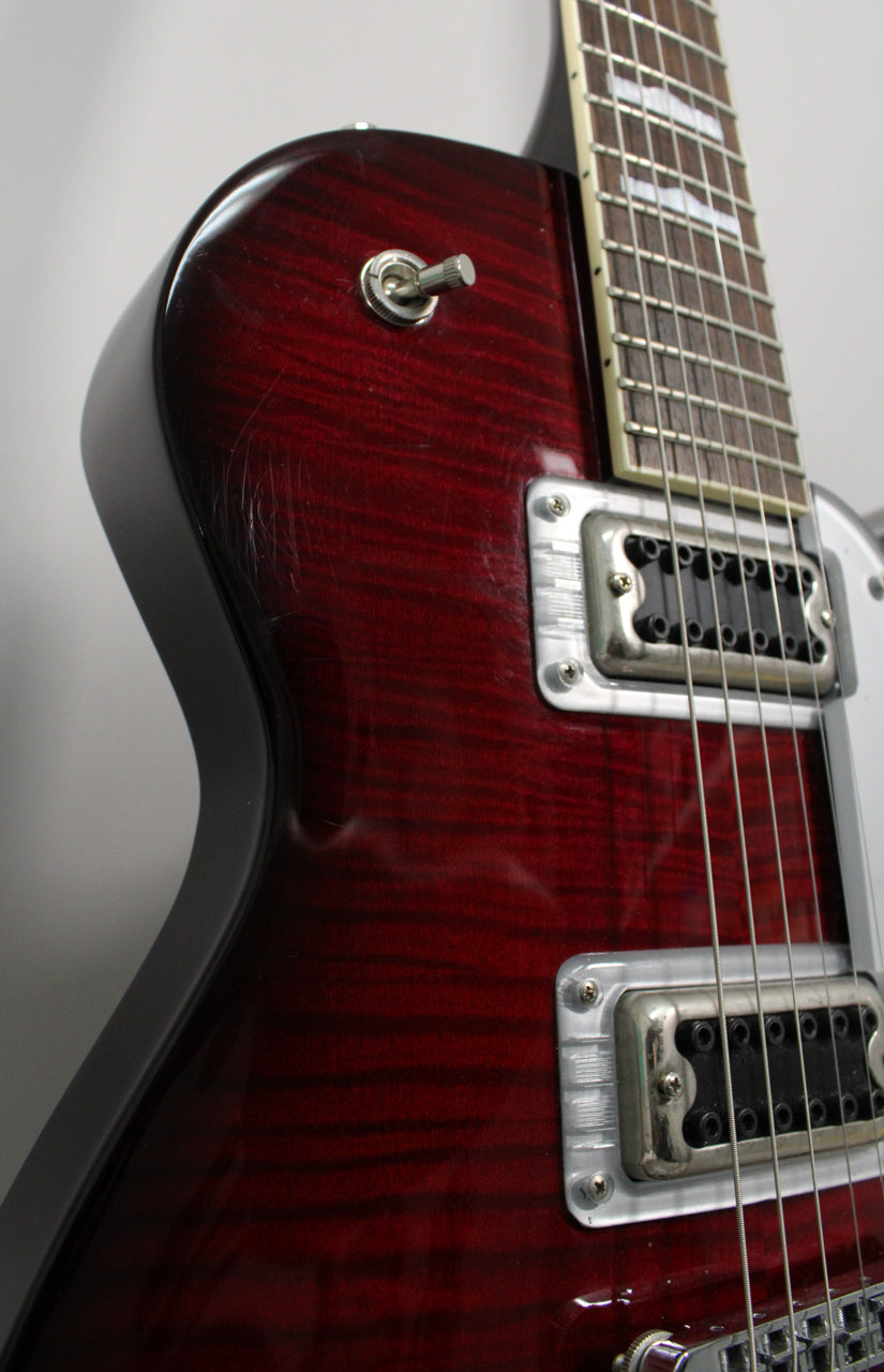 Close-up of the guitar's upper body, showing the transparent red finish with wood grain, a pickup selector switch, and visible scratches.