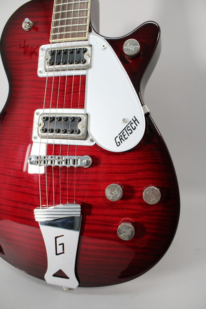 Close-up of the transparent red flamed maple body, showing the pickups, bridge, white pickguard, and four silver control knobs.