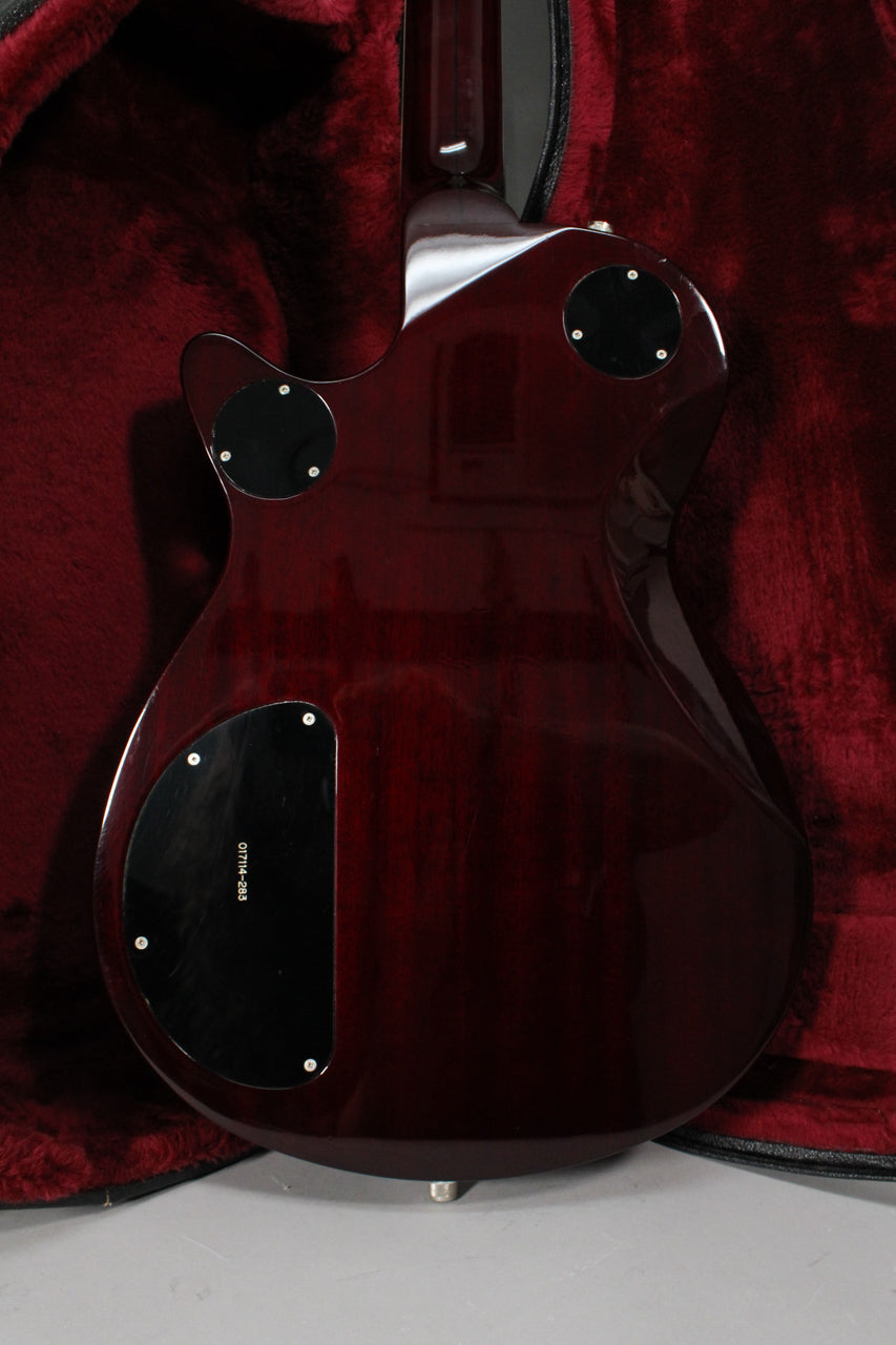 The guitar's transparent red back, revealing wood grain, features three black control cavity covers and a chrome strap button.