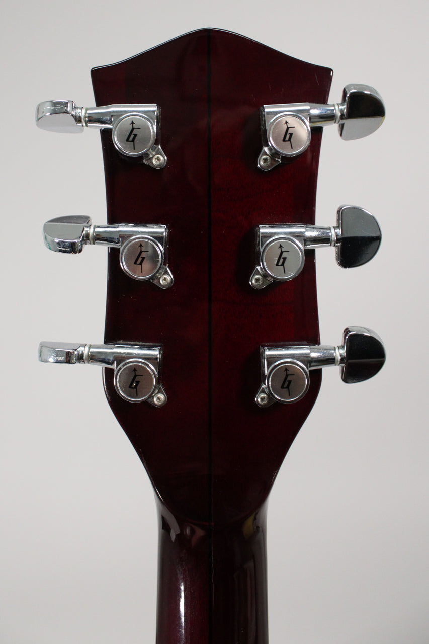 The back of a dark red guitar headstock with a glossy finish, showing six chrome tuners with "G" logos.