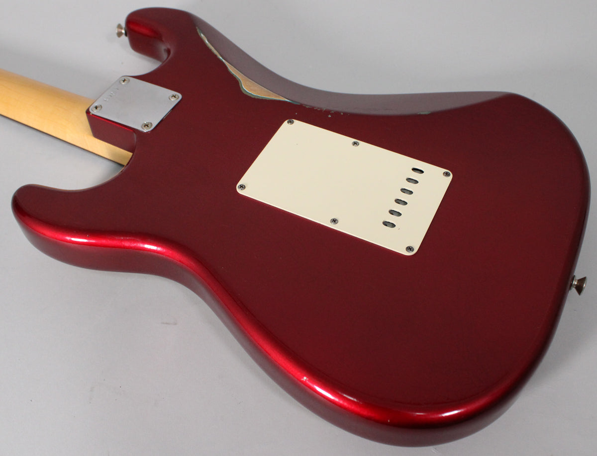 The back of a Candy Apple Red Stratocaster, showing the tremolo cover, neck plate, and significant finish wear on the upper horn.