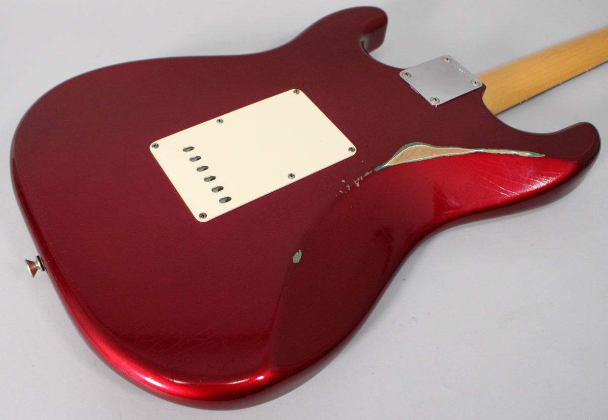 The back of the Candy Apple Red body shows a large chip revealing wood, heavy scratching, and a cream tremolo cover.