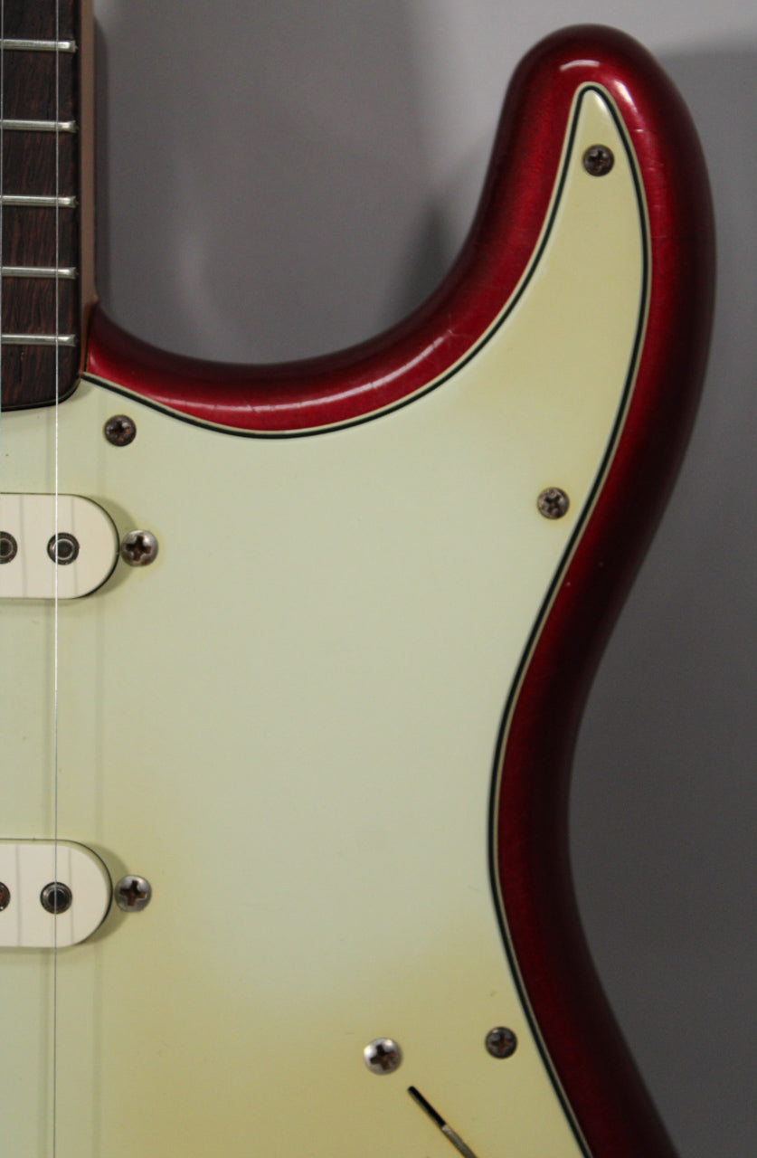 Close-up of the upper body horn and neck joint, showing the Candy Apple Red finish with checking and a cream pickguard.