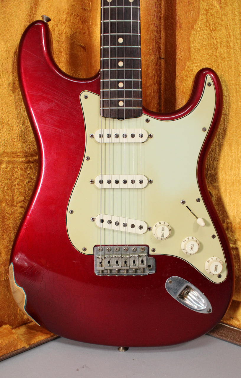 Full view of a relic'd Candy Apple Red Stratocaster with a cream pickguard, three single-coil pickups, and visible finish checking.