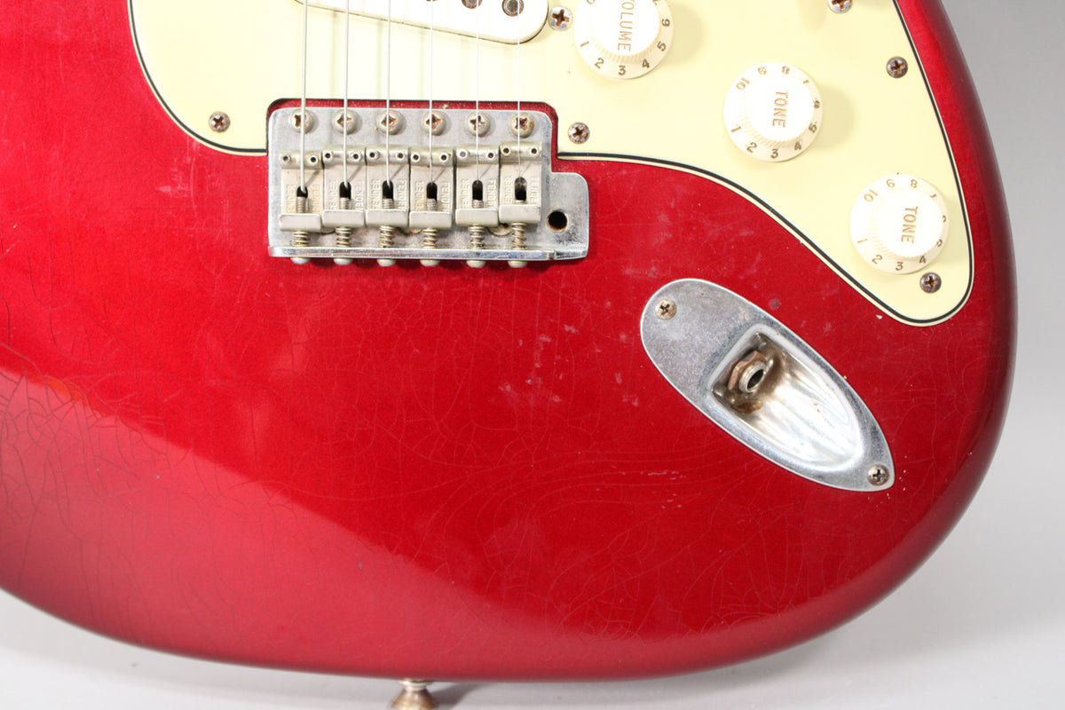Close-up of the lower body, showing the red finish with extensive checking, the bridge, and the input jack.