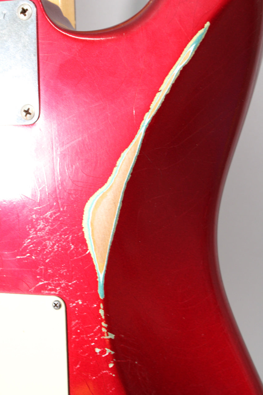 Close-up of the guitar body's upper bout, showing a large chip in the Candy Apple Red finish revealing a light blue undercoat.