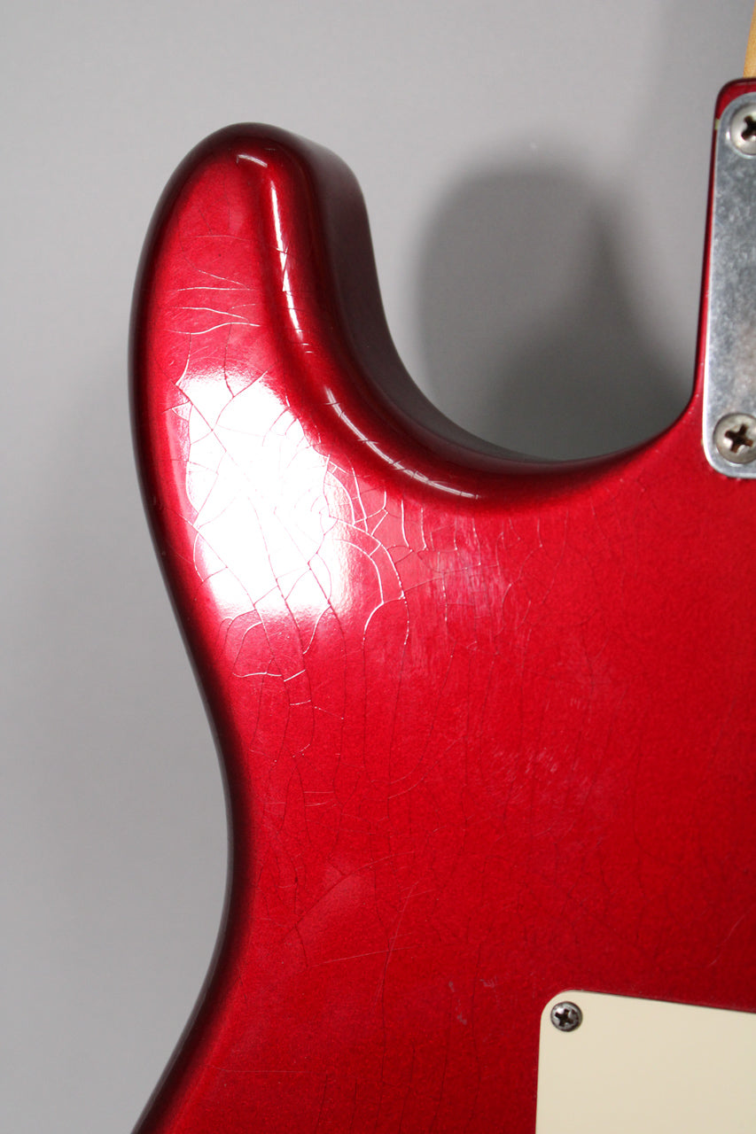 Close-up of the upper horn and cutaway, showing extensive finish checking and wear on the metallic red body.