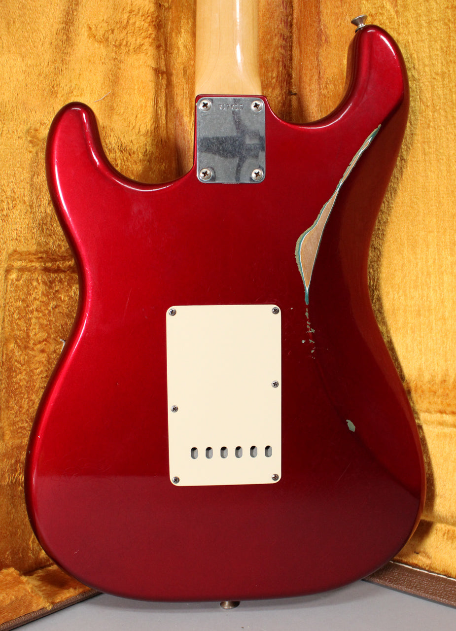 Rear view of a Candy Apple Red Stratocaster body with a large paint chip on the upper bout revealing wood and a light blue undercoat.