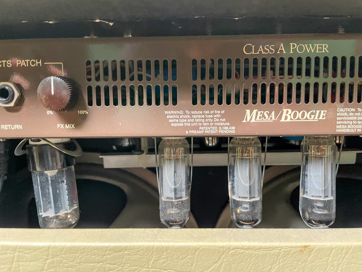 Close-up of the amp's rear, showing four glowing vacuum tubes, a brown metal grille, and an "FX MIX" knob.