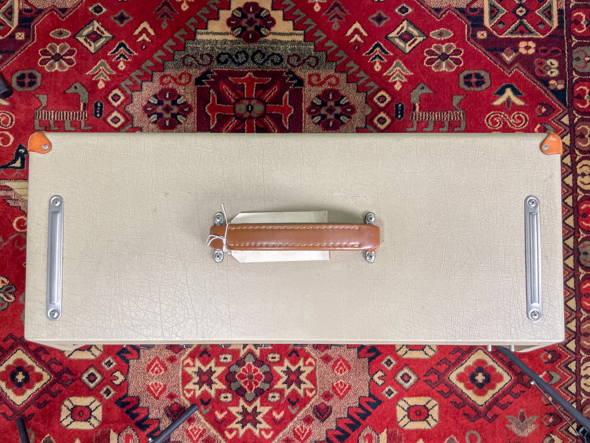 Top-down view of the amp's light beige textured tolex cabinet, showing the brown leather handle and silver metal side rails.