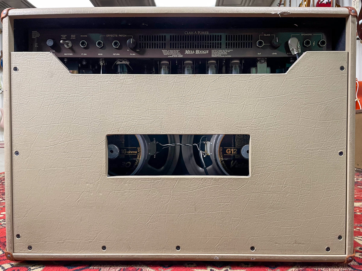 Rear view of the tan textured combo amp, showing the control panel, exposed tubes, and two speaker cutouts revealing the cones.