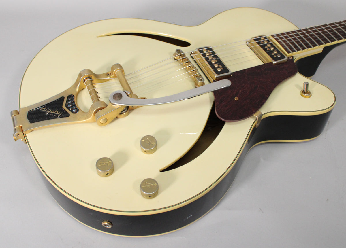 Upper body of an antique white hollow-body electric guitar, showing gold hardware, f-holes, and a dark tortoise shell pickguard.