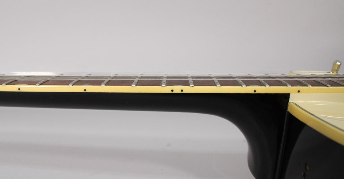 Side view of the guitar's dark neck and rosewood fretboard with dot inlays, showing cream binding and light fret wear.