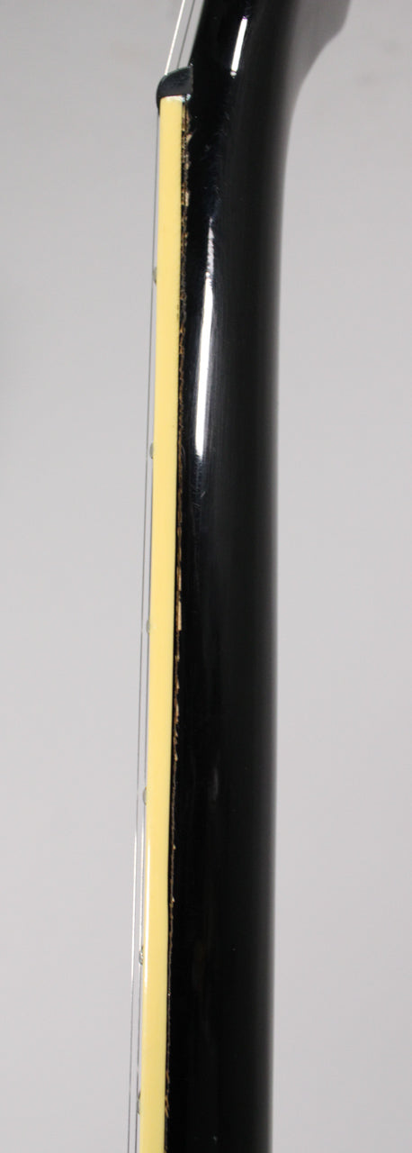 Close-up of the guitar's black neck and cream binding, showing finish wear and chipping along the binding edge.
