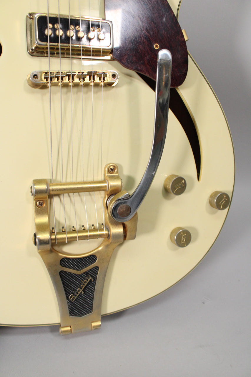 Close-up of the antique white body, showing a gold Bigsby vibrato, gold bridge, gold pickup, and three gold control knobs.