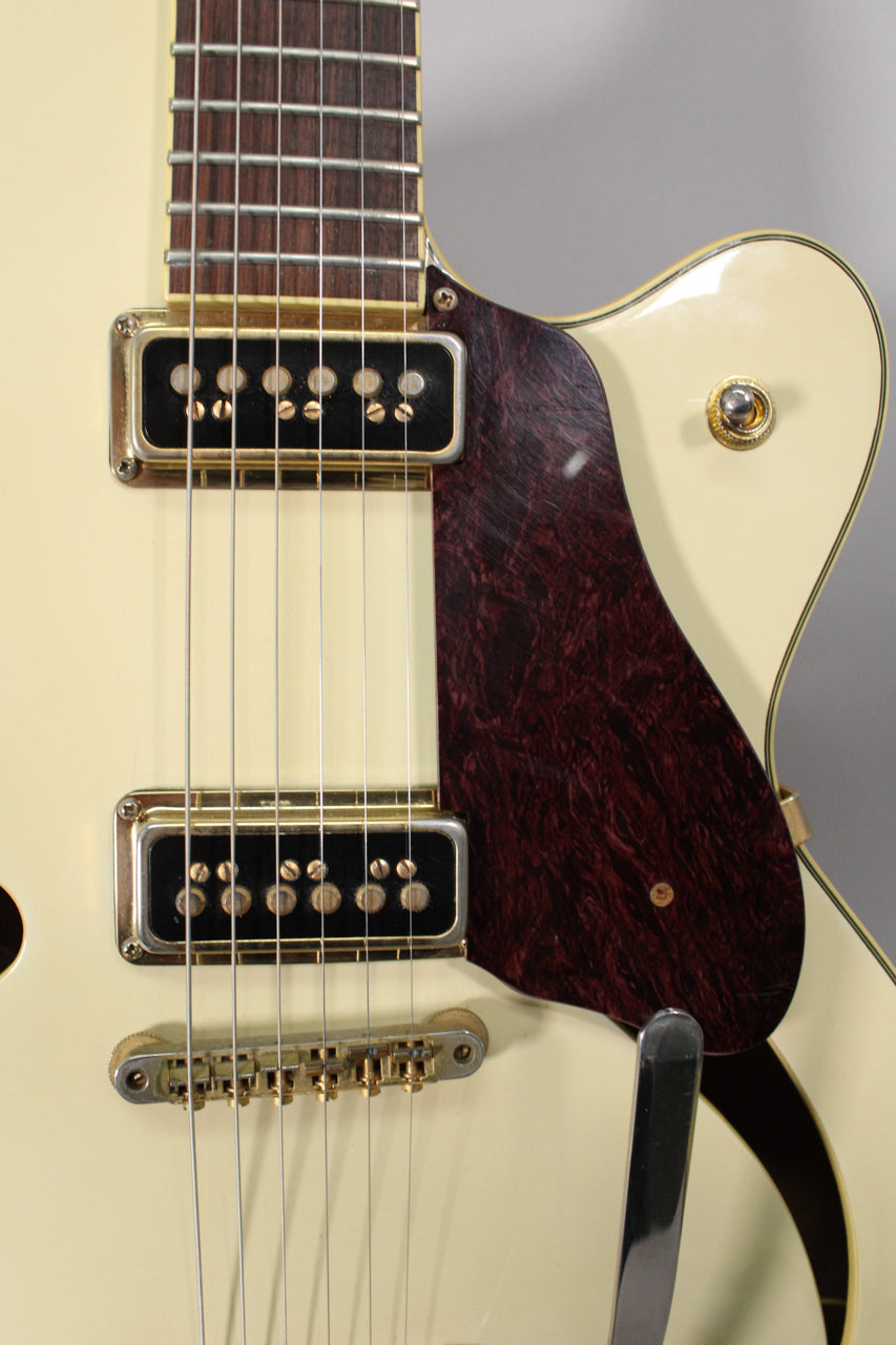 Close-up of the antique white body, showing two gold-covered pickups, a dark red tortoiseshell pickguard, and a gold bridge.