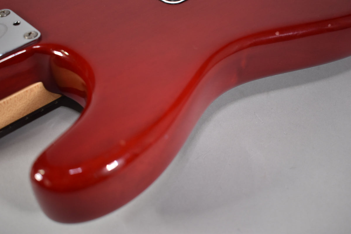 Close-up of the guitar's lower horn in glossy crimson red, showing the neck pocket and chrome neck plate.