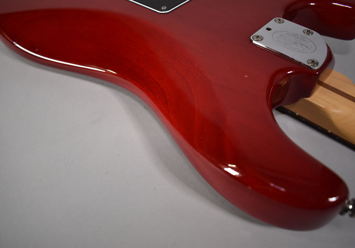The crimson red Stratocaster body, with visible wood grain, shows a chrome neck plate and a small ding on the lower bout.
