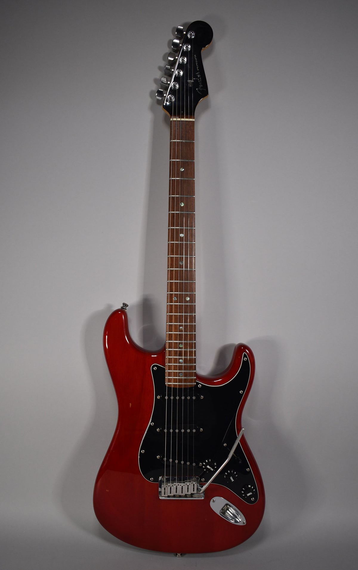 Full-length view of a glossy crimson red Stratocaster with a black pickguard, three single-coil pickups, and chrome hardware.