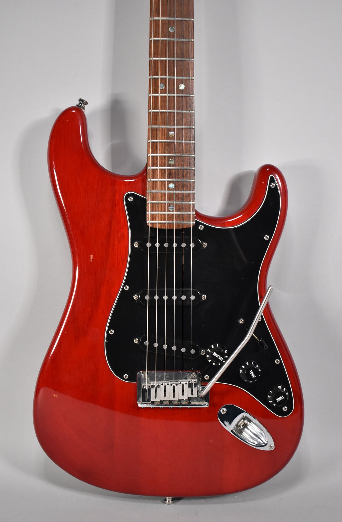 Crimson red Stratocaster, angled from the lower body to the neck, with a black pickguard, three black pickups, and chrome hardware.