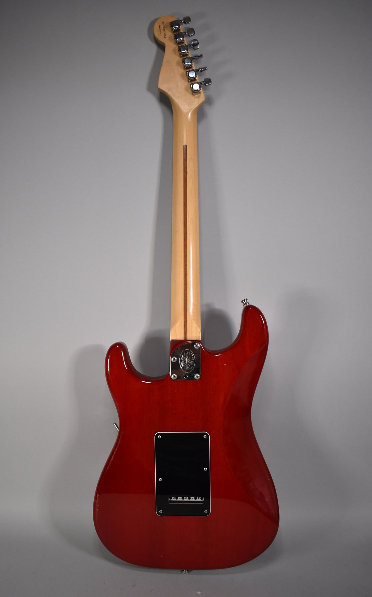 Full rear view of a crimson red Stratocaster with a maple neck, chrome tuners, and a black tremolo cover.