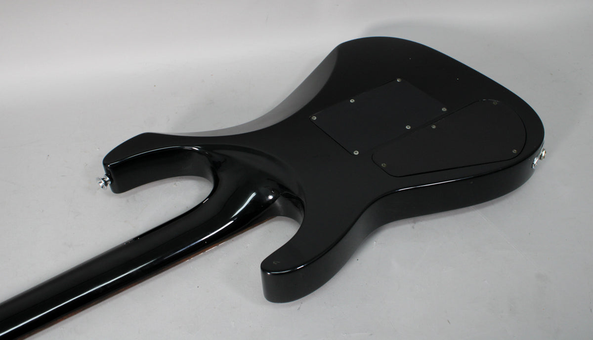 The back of the black guitar body, showing the neck joint, two control cavity covers, and some minor scuffs on the glossy finish.