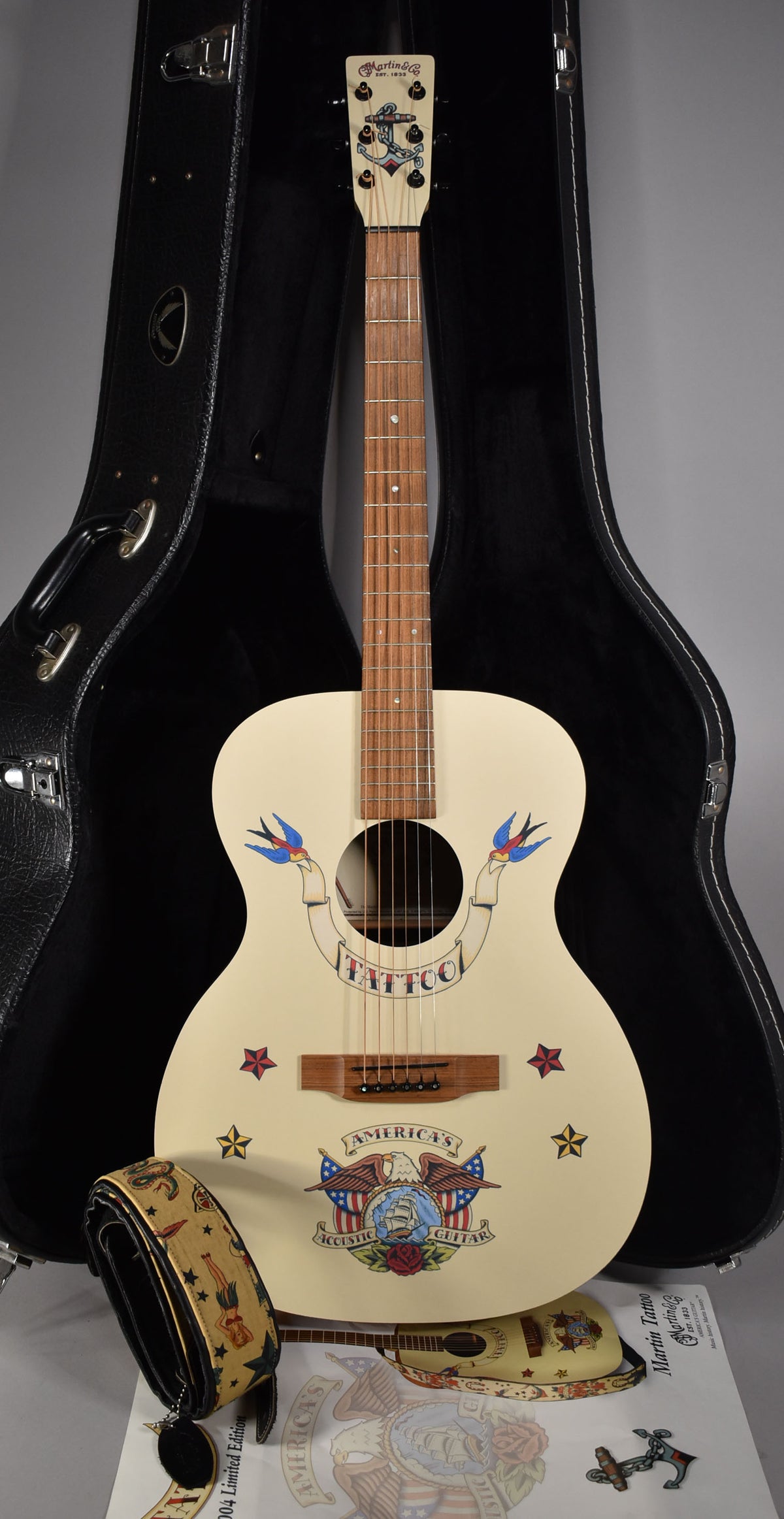 Full-length, front-facing view of a cream acoustic guitar with colorful tattoo-style graphics, including an eagle and swallows.