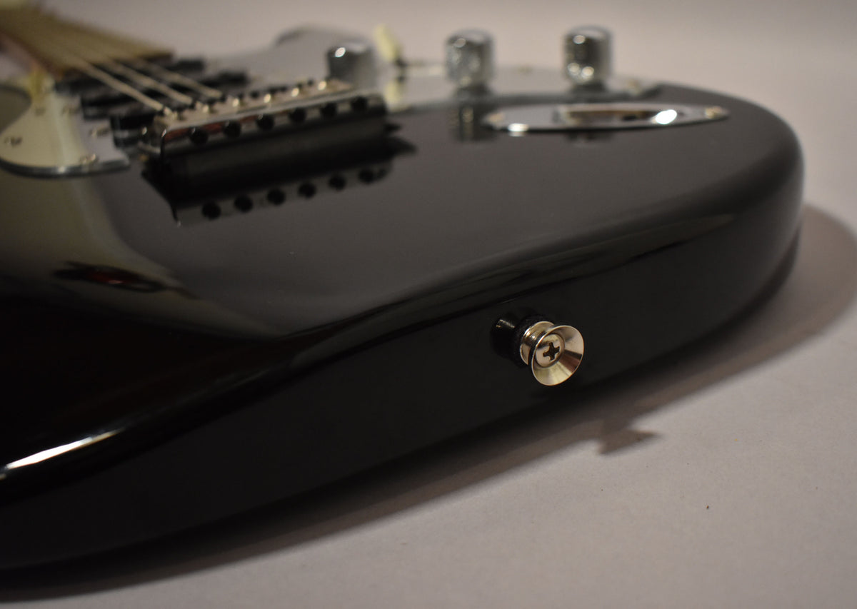 The black electric guitar's lower bout and output jack are visible, with the bridge and controls blurred in the background.