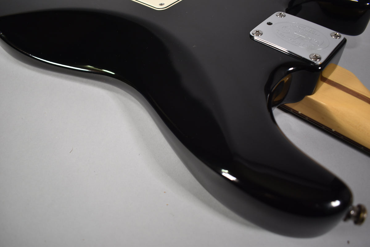Close-up of the guitar's lower horn and neck joint from the back, showing the glossy black finish and chrome neck plate.