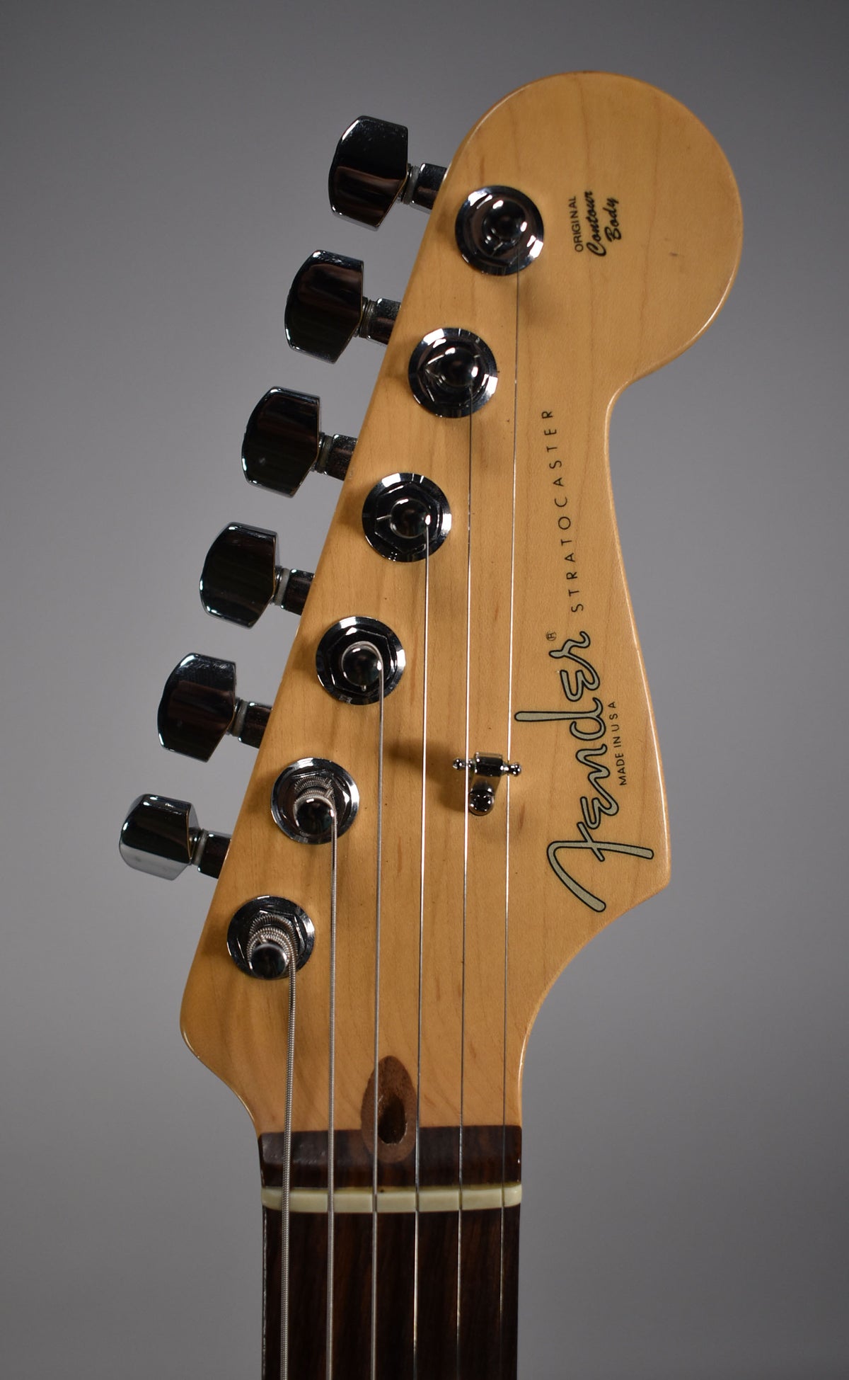 Close-up of the guitar's headstock and nut, showing six chrome tuners, a string tree, and a dark rosewood fretboard.