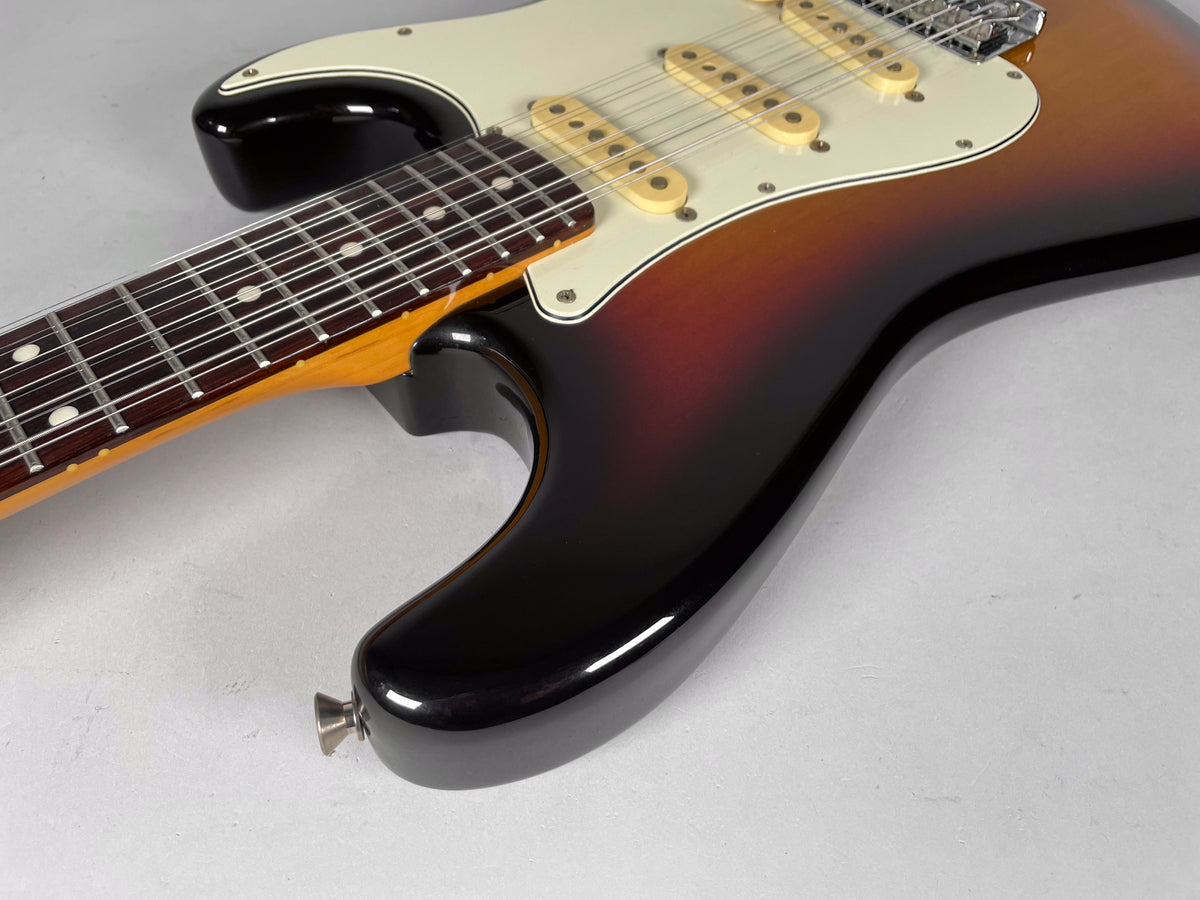 Close-up of the sunburst body and neck joint, showing the lower horn, white pickguard, three cream pickups, and dark fretboard.