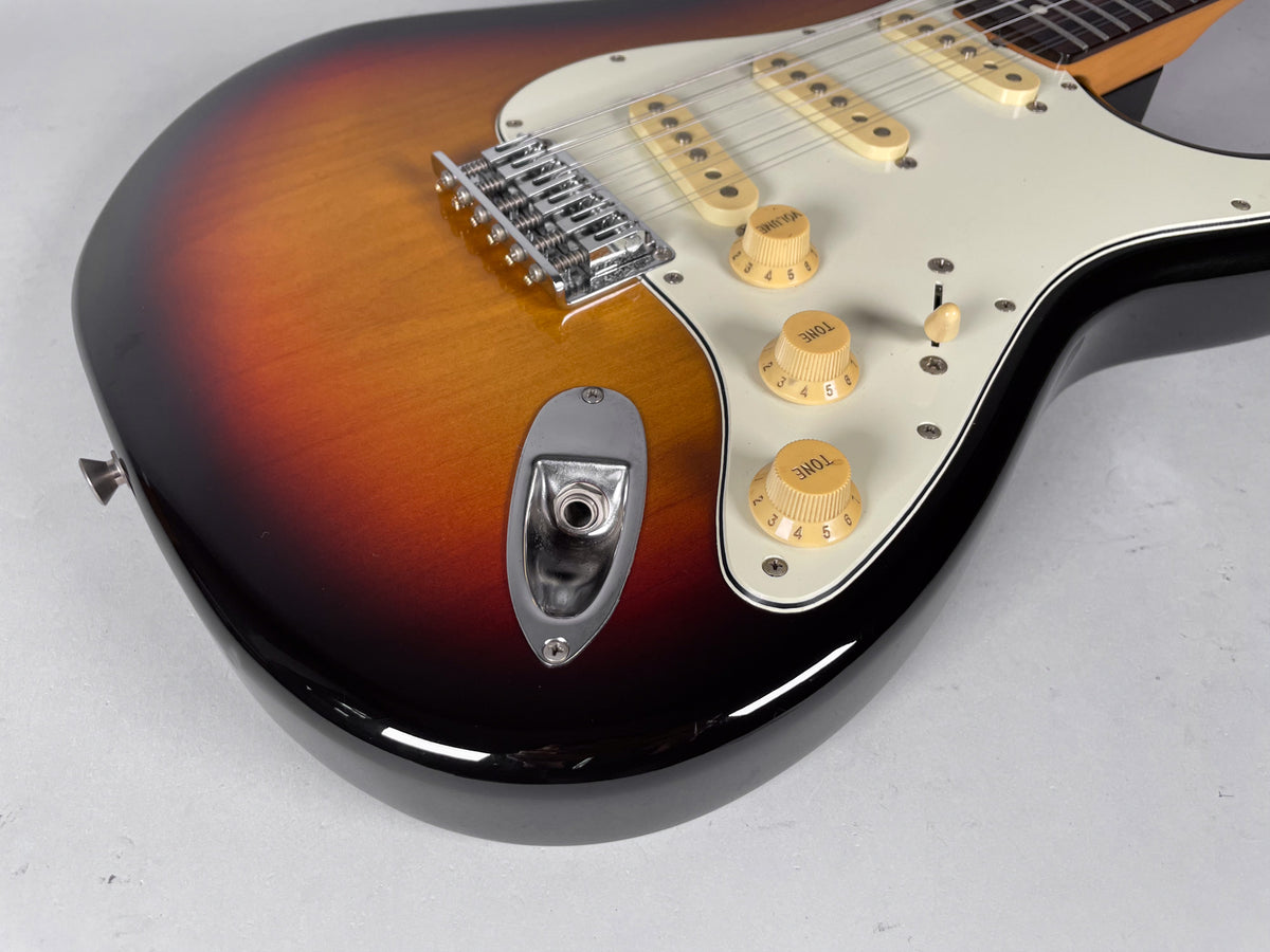 Upper body of a sunburst 12-string electric guitar, angled to show the chrome bridge, white pickguard, and cream controls.