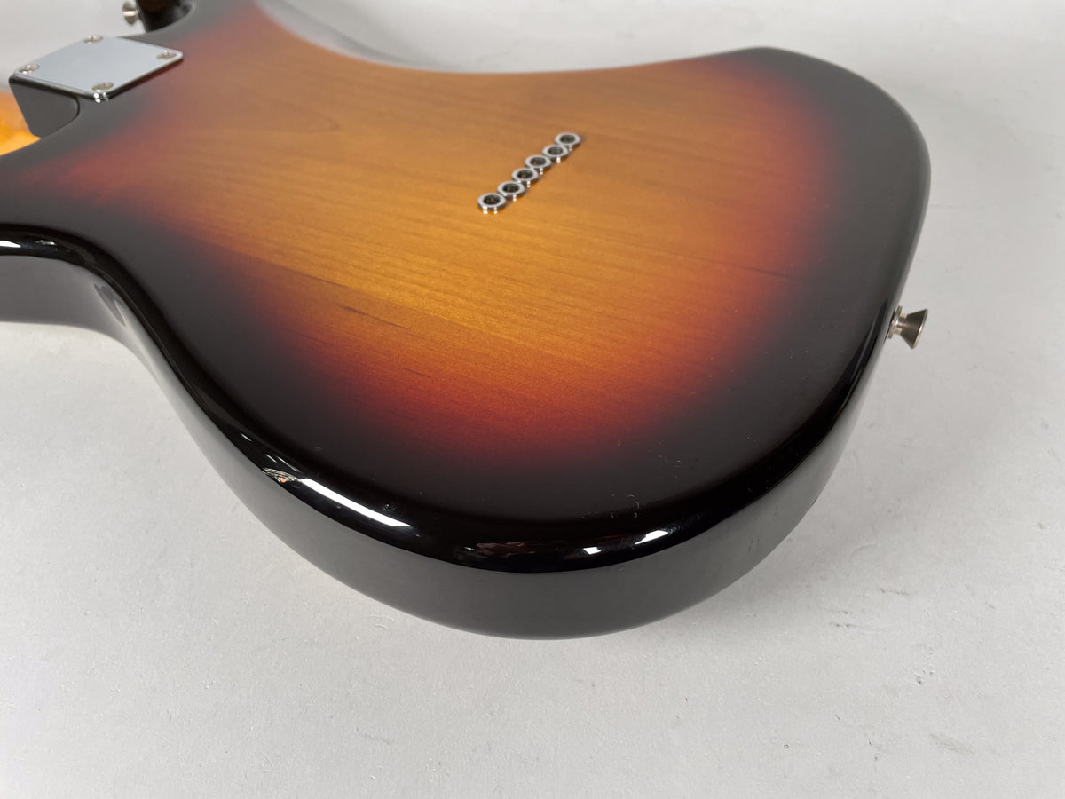The lower bout of a sunburst 12-string electric guitar, showing the strap button and a chip in the finish on the bottom edge.