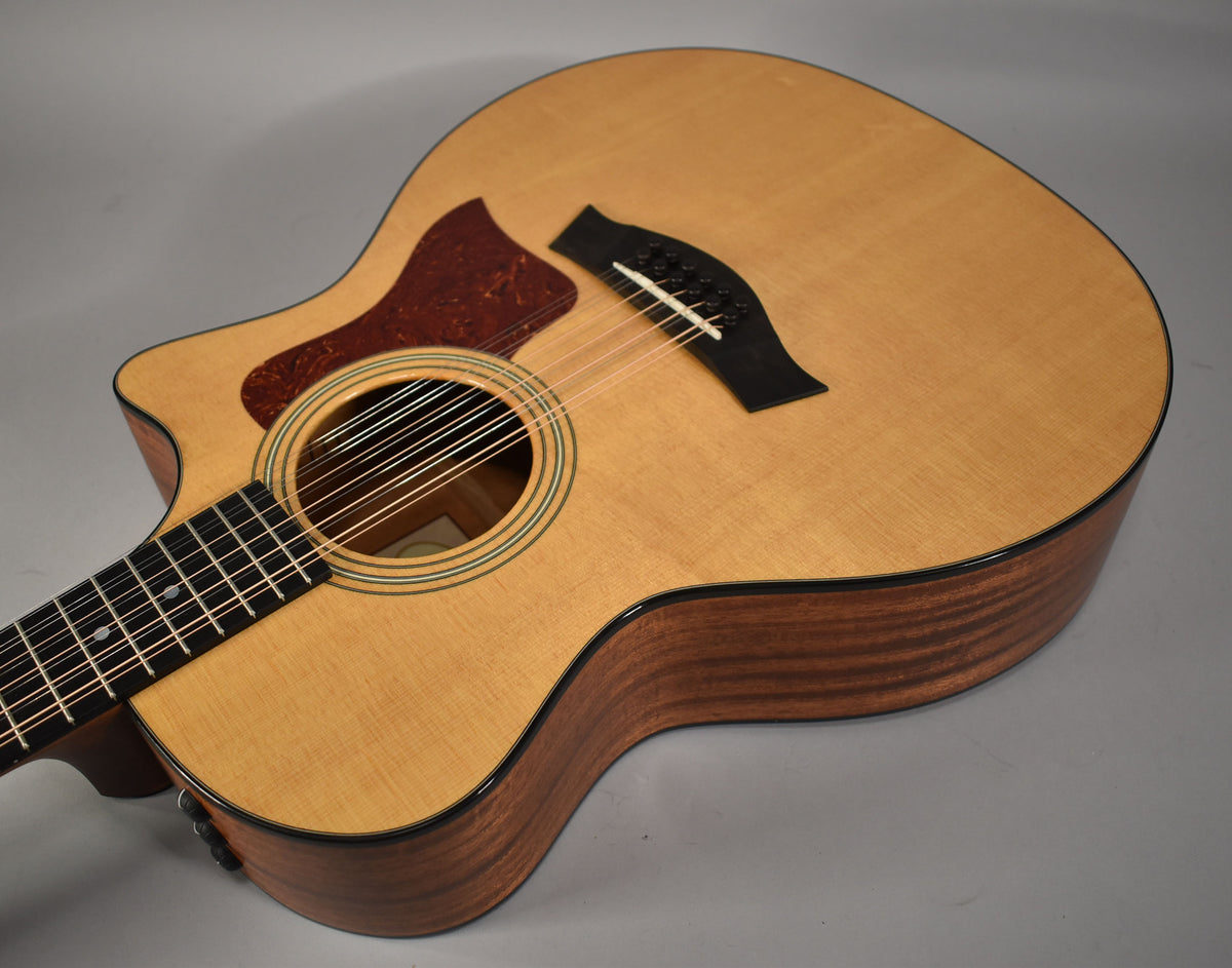 Light wood 12-string acoustic guitar, angled from the neck to the lower bout, showing the cutaway and dark wood sides.