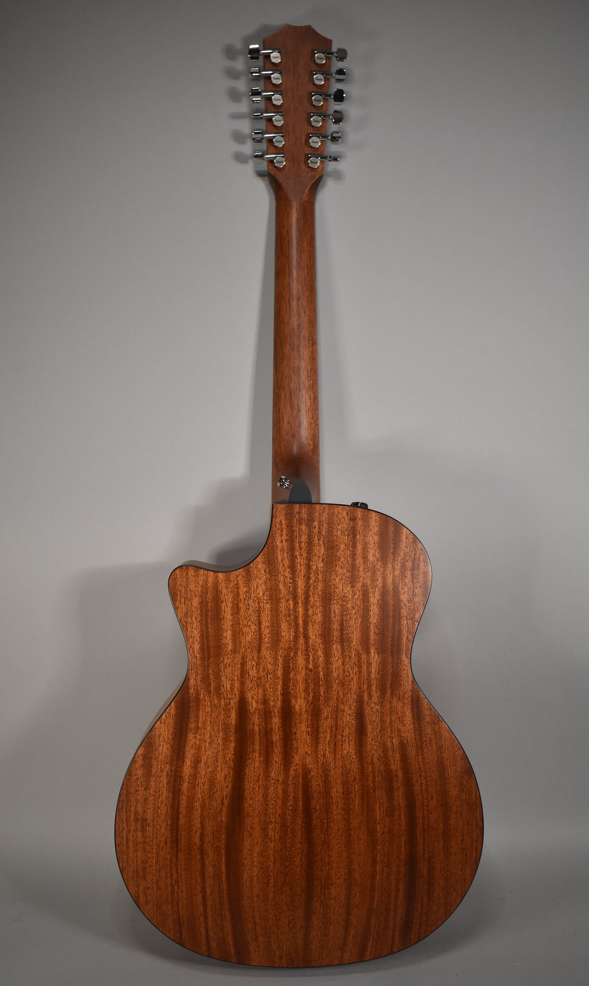 Full rear view of a natural finish 12-string acoustic guitar with a cutaway, showing the mahogany back, neck, and headstock with chrome tuners.