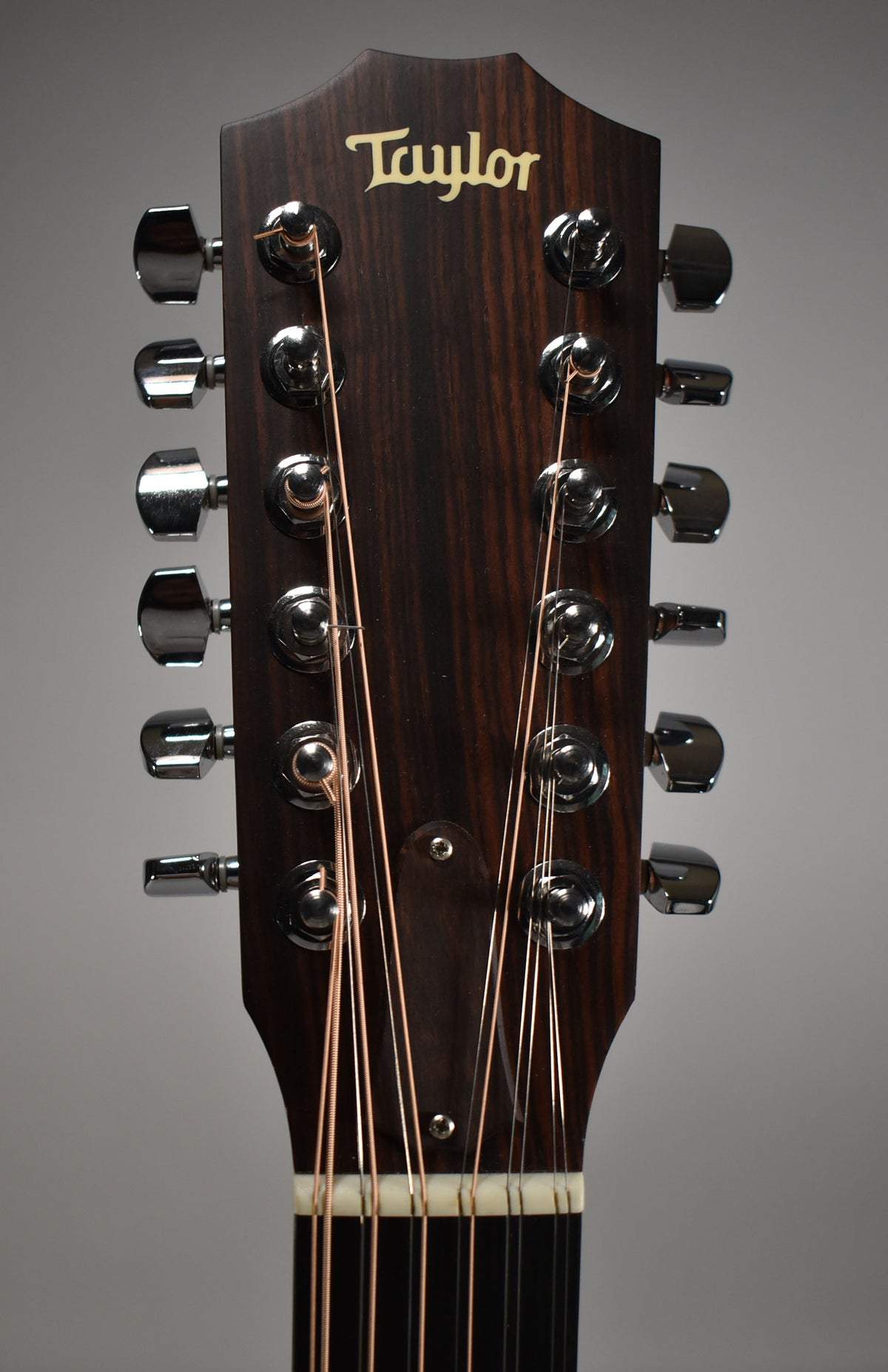 Close-up of the dark wood headstock with a light logo, showing 12 chrome tuners and bronze strings.