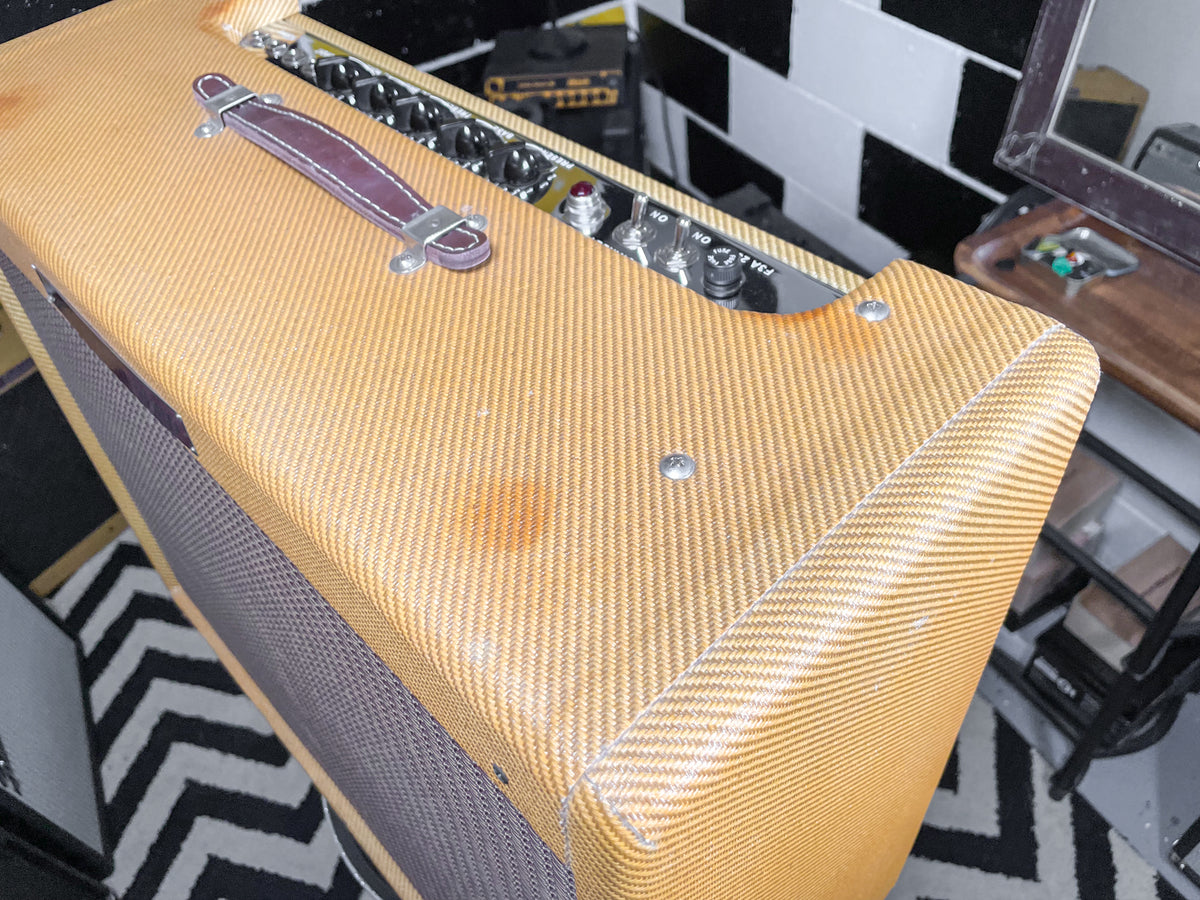 Top-down view of a tweed combo amp with a dark brown leather handle, showing a few dark spots and scuffs on the top.