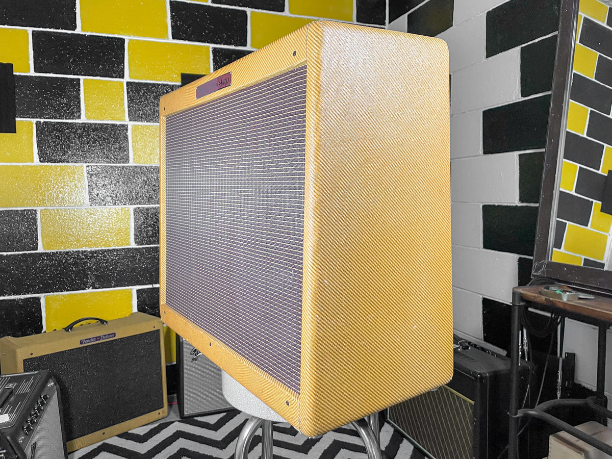 Tweed combo amp, angled to show the textured tan cabinet and dark gray grille cloth, with a small purple badge on top.