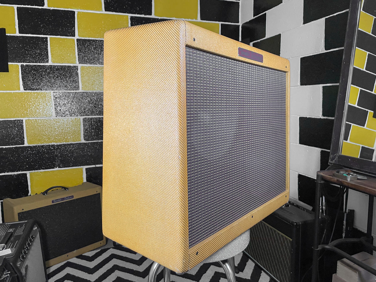 Tweed combo amp, angled to show the textured tan cabinet and dark gray grille cloth, with a small purple rectangle at the top.