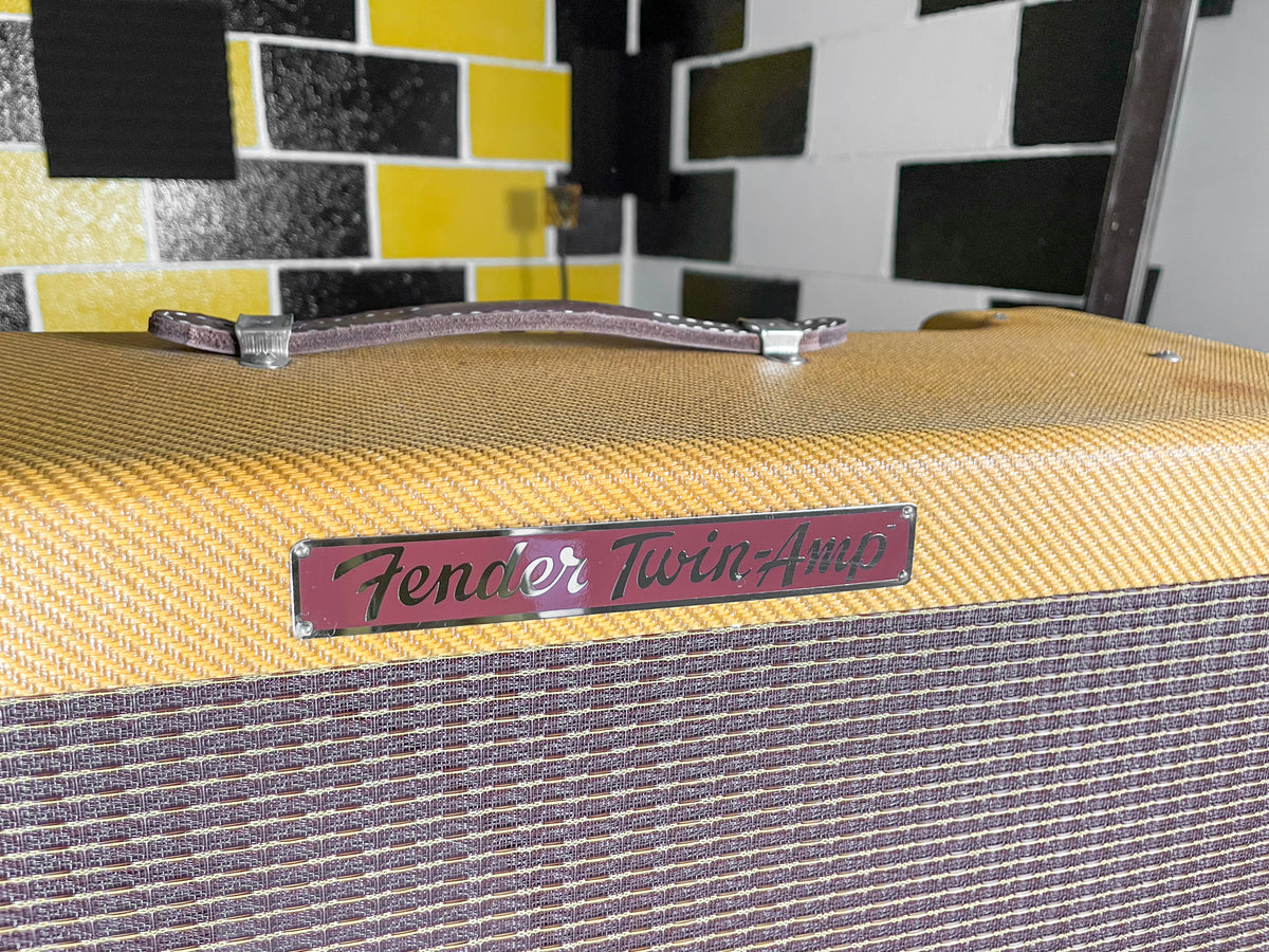 Close-up of the amp's top and upper front, showing the tweed covering, brown leather handle, and a dark red nameplate.