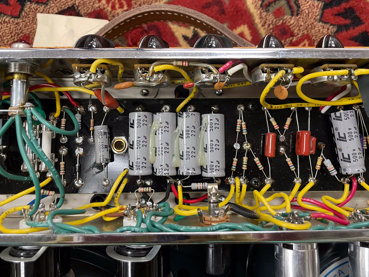Close-up of the amp's internal wiring, showing neatly arranged yellow, green, and red wires, capacitors, and resistors on a black board.