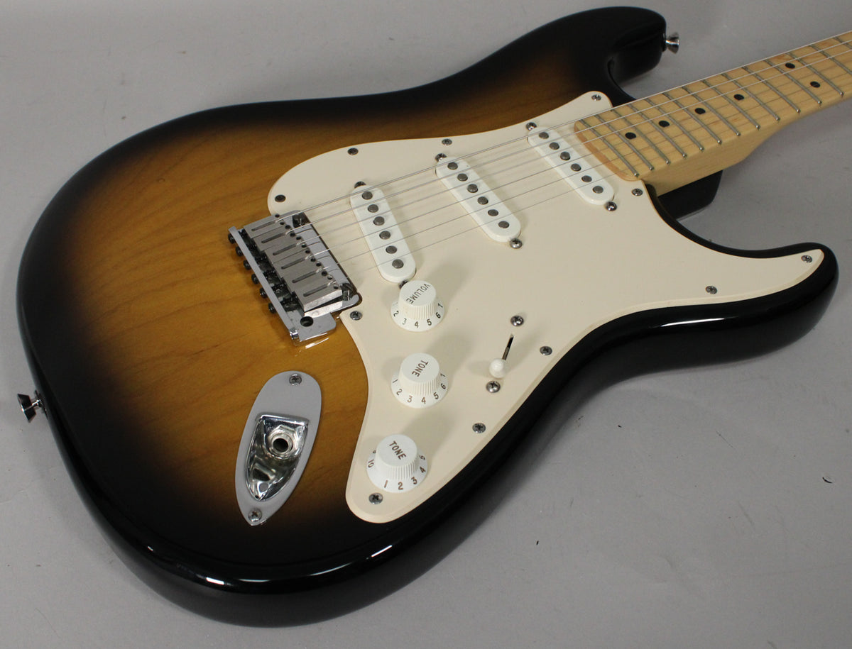 The sunburst Stratocaster's body is angled from the upper left, showing its white pickguard, three single-coil pickups, and chrome bridge.