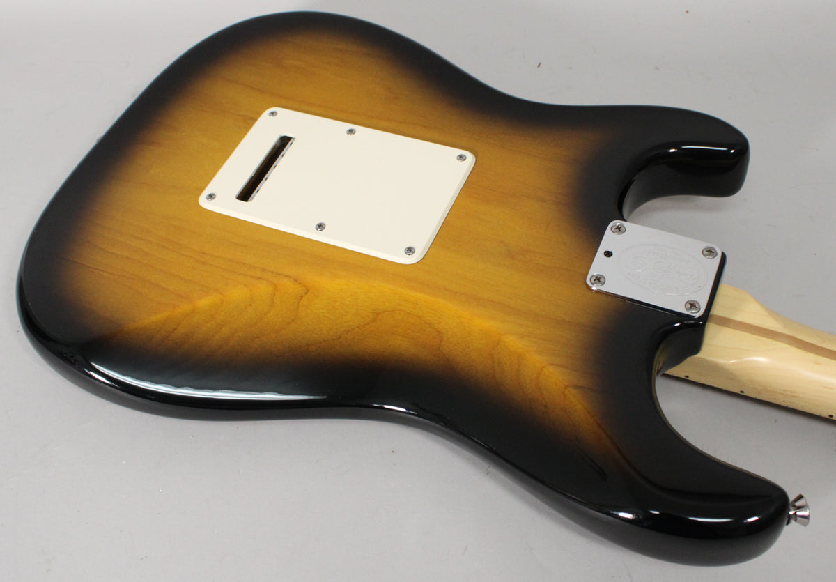 Rear view of a 2-color sunburst Stratocaster body with a cream tremolo cover, chrome neck plate, and a light wood neck.