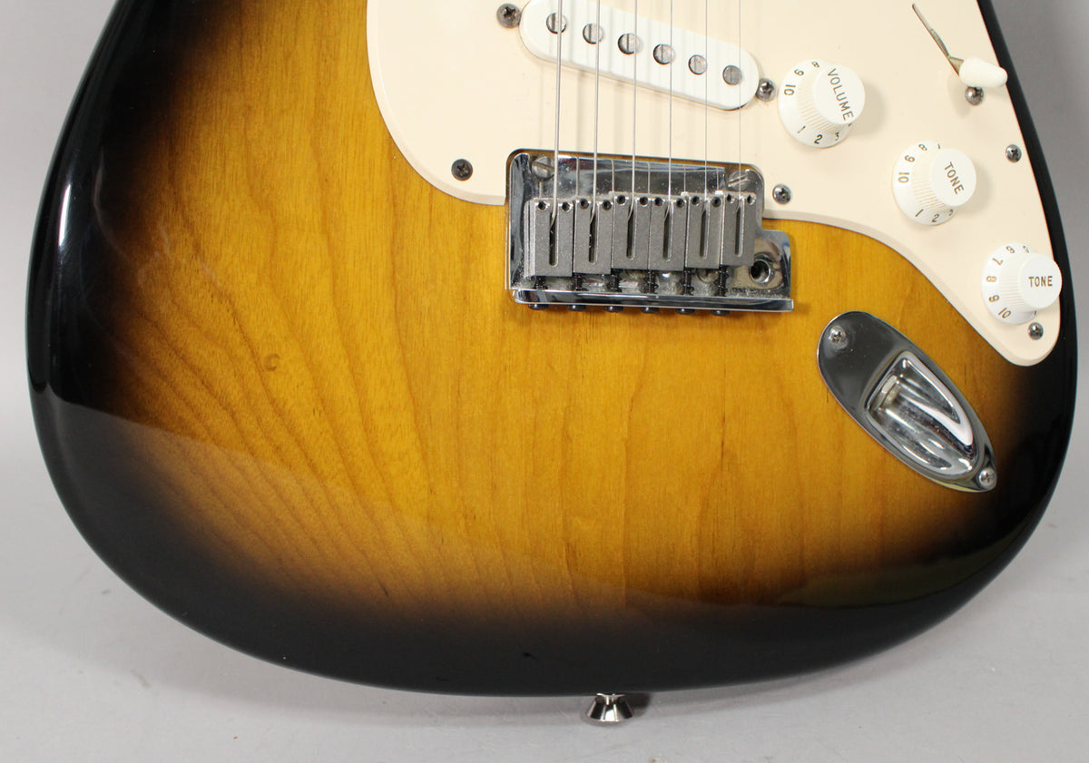 Close-up of the guitar's lower body, showing the 2-color sunburst finish, cream pickguard, chrome bridge, and output jack.
