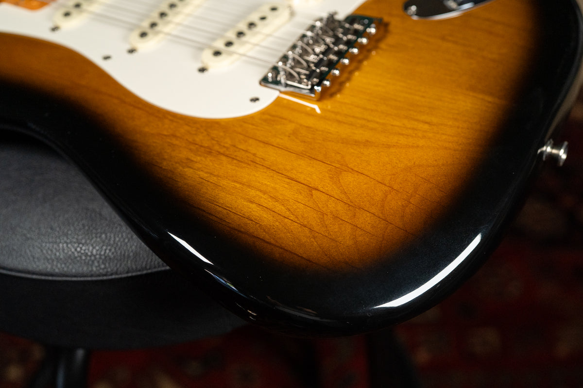 Close-up of the guitar's lower body, showing the sunburst finish with visible light scratches and the chrome tremolo bridge.